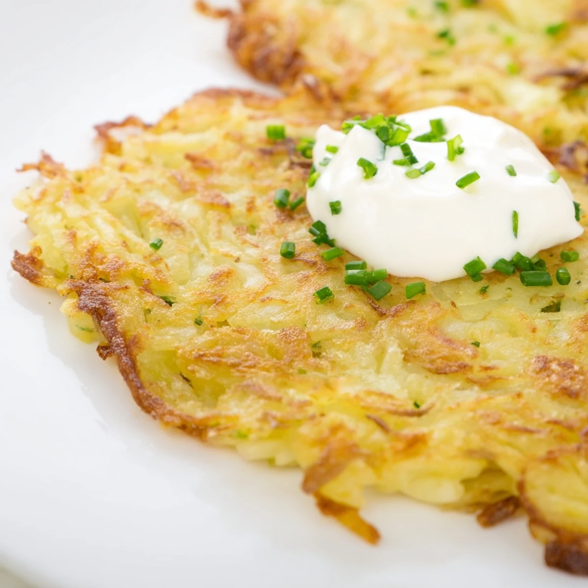 Golden-brown Irish Boxty Potato Pancakes with Scallions rest on a plate, showcasing a crispy outer edge and soft, fluffy interior.