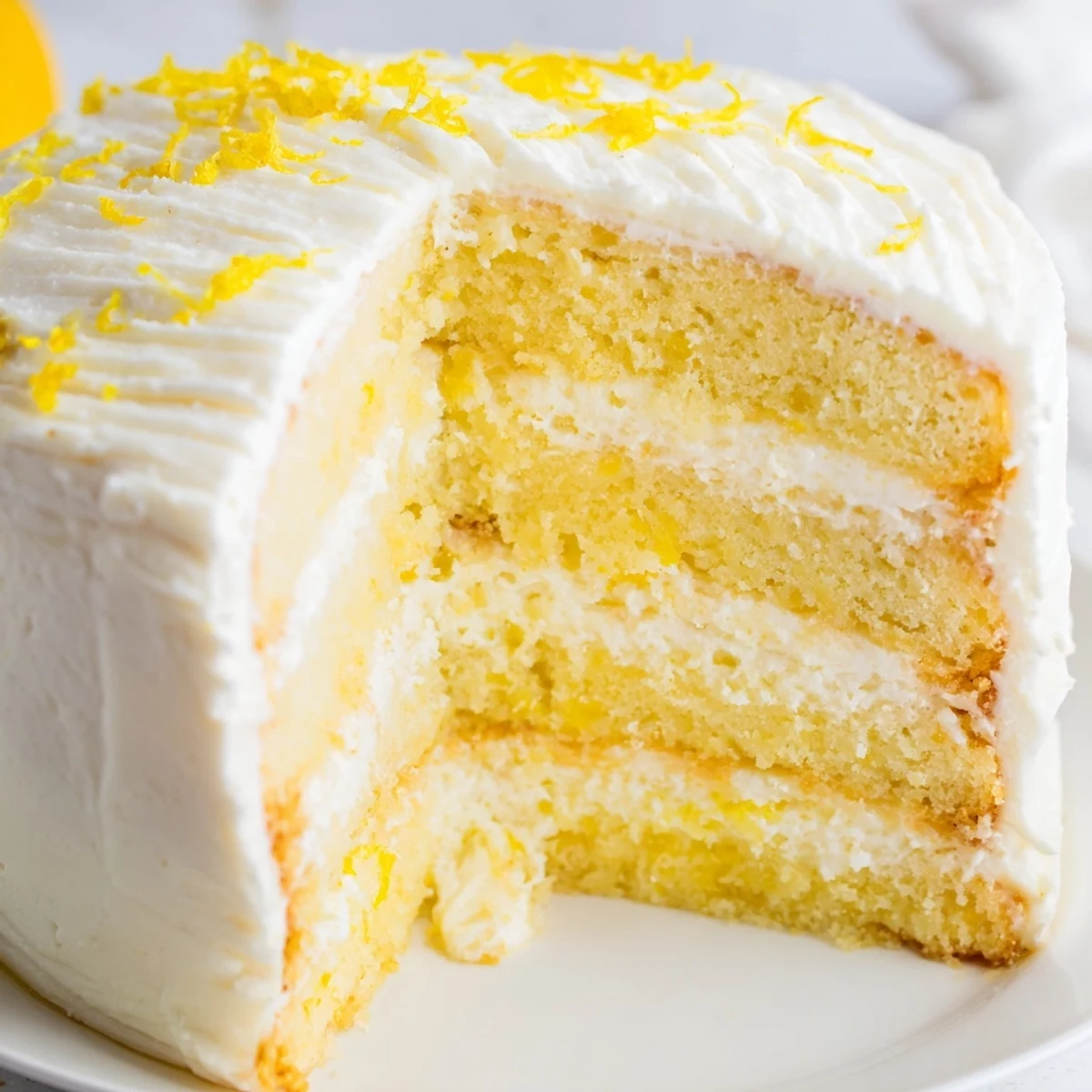 Overhead view of a plated Limoncello Mascarpone Cake glistening with limoncello syrup and topped with delicate edible flowers.