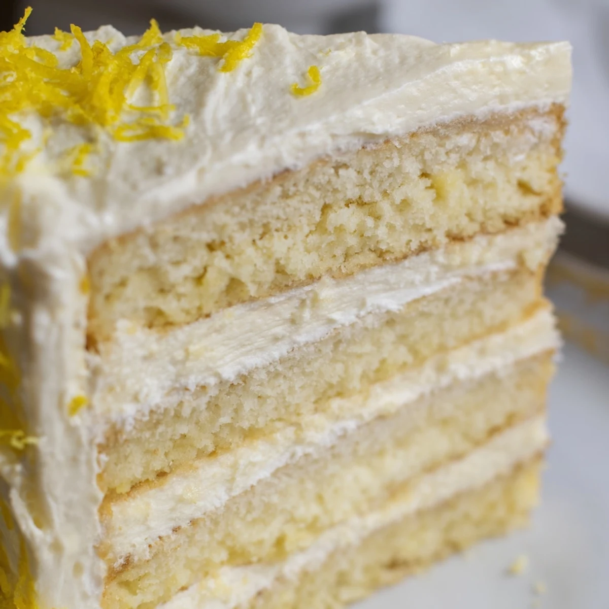 On a marble counter, Limoncello Mascarpone Cake layers sit beside lemon slices and mascarpone filling, ready to be assembled.