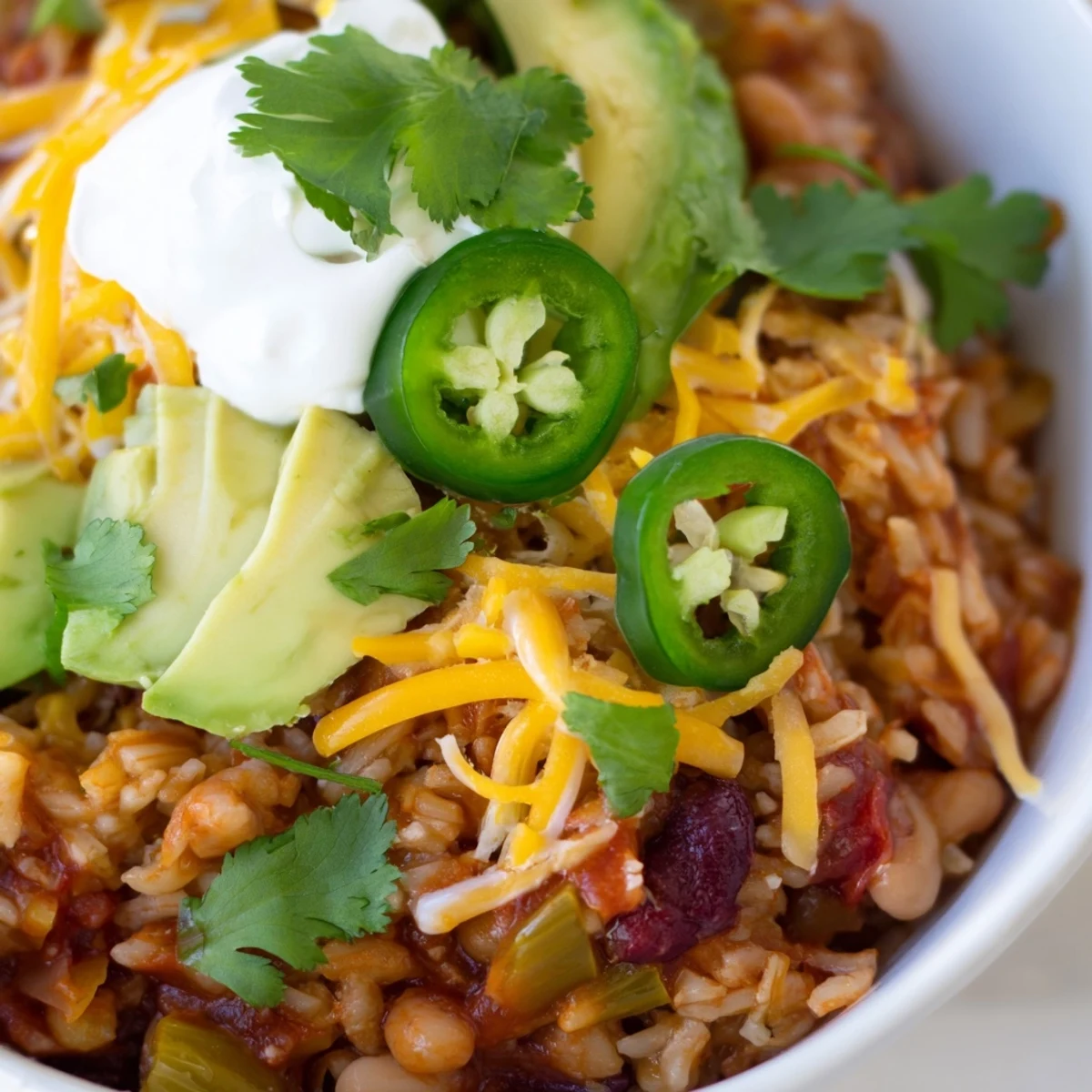 Close-up of a Southwest Spice Green Chile Bowl with toppings like avocado and cheese on a rustic table.