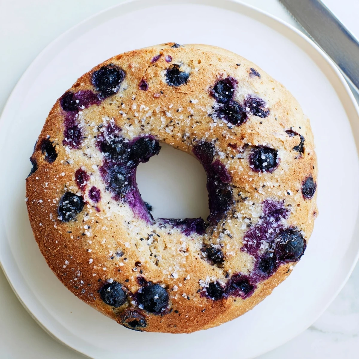Sliced gluten-free blueberry bagels on a wooden board, showcasing the soft, chewy texture and bursting berries.