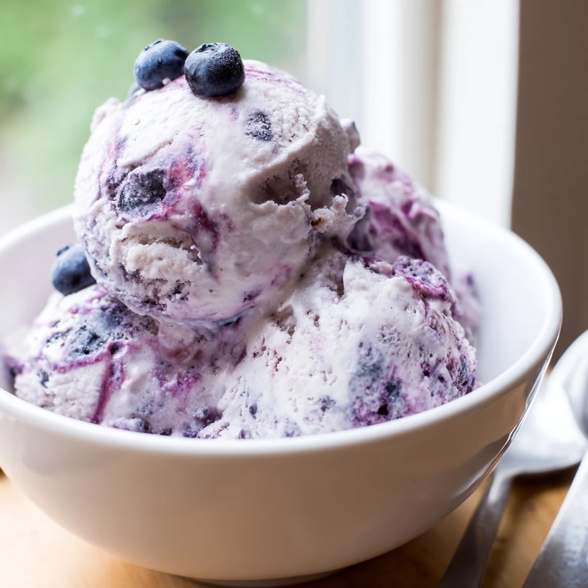 Scoop of protein-rich Blueberry Cottage Cheese Ice Cream topped with fresh berries and a drizzle of honey.