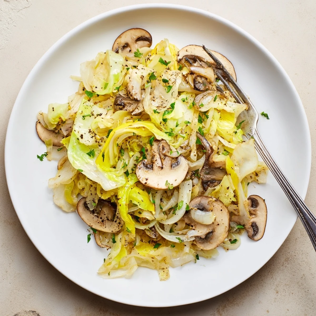 A close-up of vegetarian cabbage mushroom sauté, golden brown and glistening in a white ceramic skillet, garnished with fresh parsley.