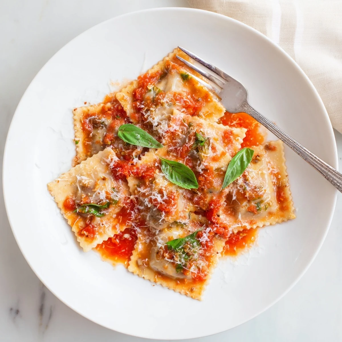 Homemade Chicken and Mushroom Ravioli with Simple Tomato Sauce, topped with fresh basil and grated Parmesan cheese.  