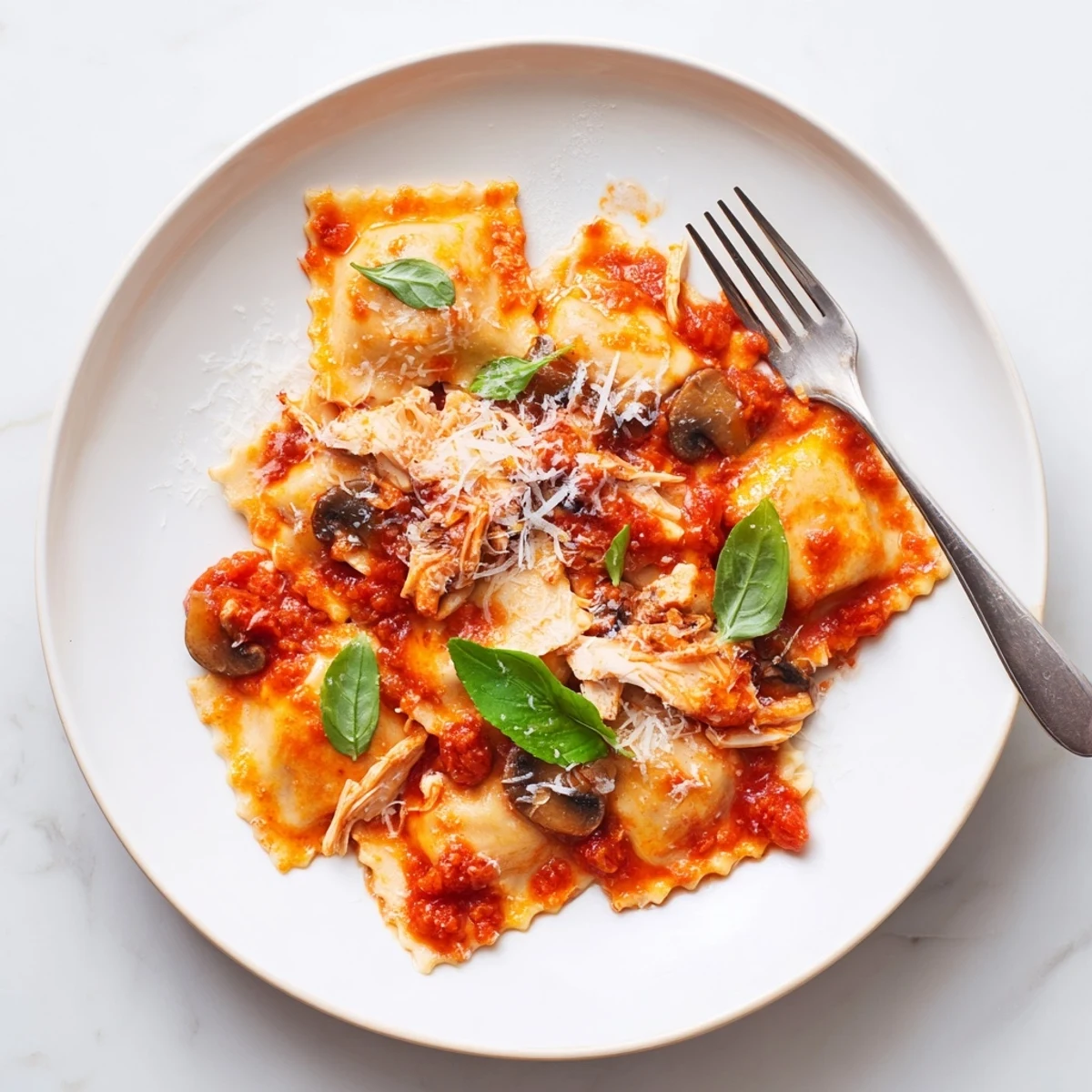 Delicate ravioli filled with tender chicken and earthy mushrooms, coated in a bright aromatic tomato sauce for a comforting meal.  
