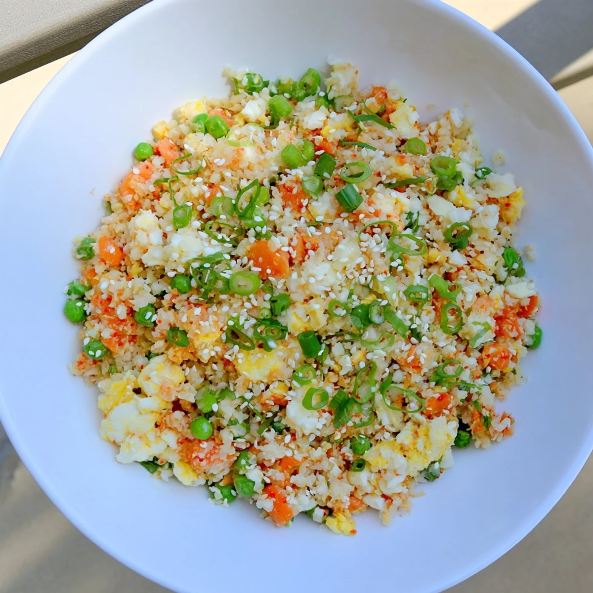 A close-up of low-carb cauliflower fried rice with kimchi, eggs, and diced carrots, ready to serve.
