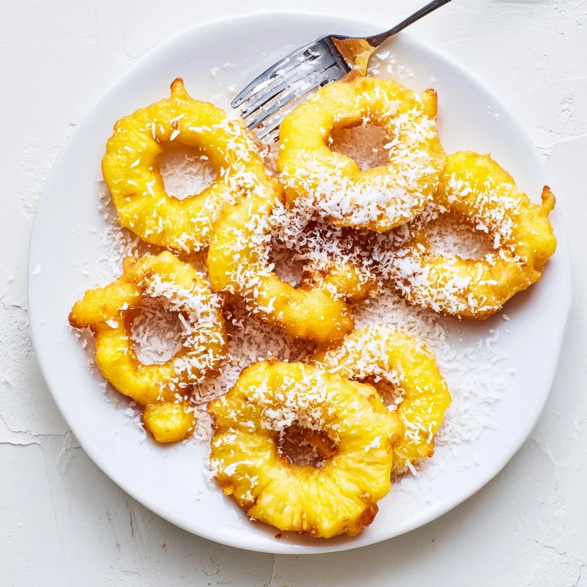 Warm tropical pineapple fritters sprinkled with powdered sugar and toasted coconut flakes