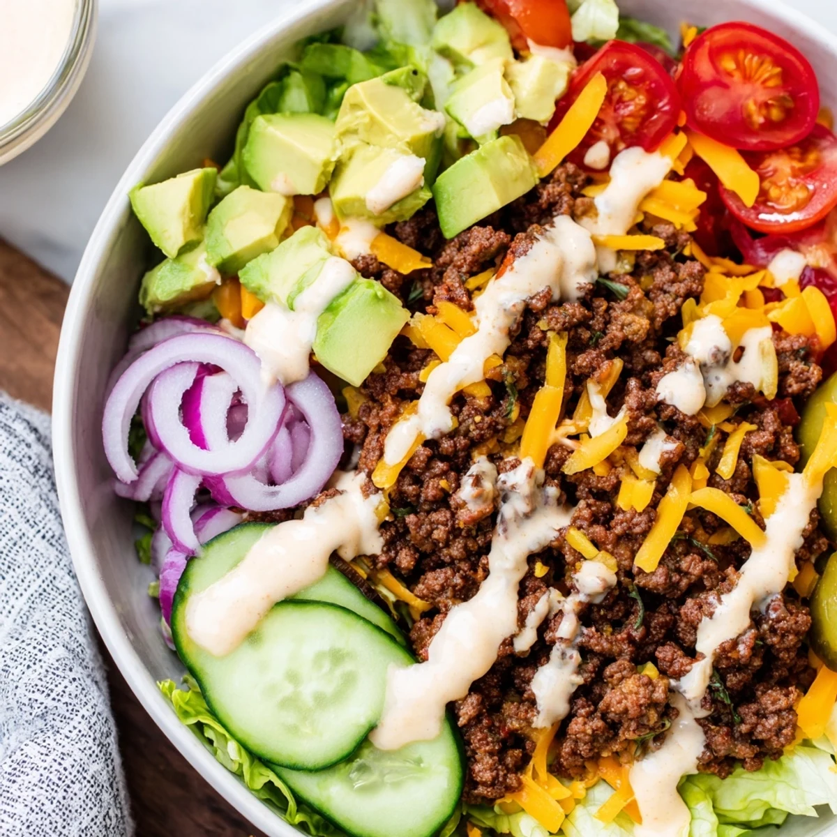 Low-carb burger bowls featuring juicy beef crumbles, cheddar cheese, avocado, and crisp vegetable toppings