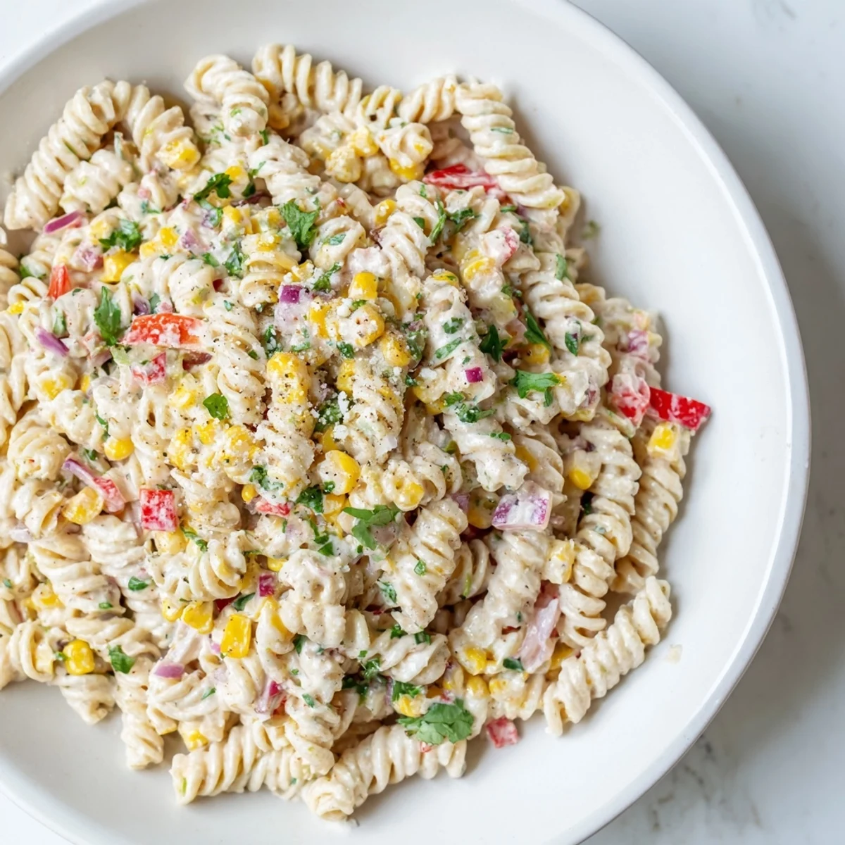 Vibrant Mexican-inspired pasta salad featuring sweet grilled corn kernels tossed in spicy lime-cilantro dressing