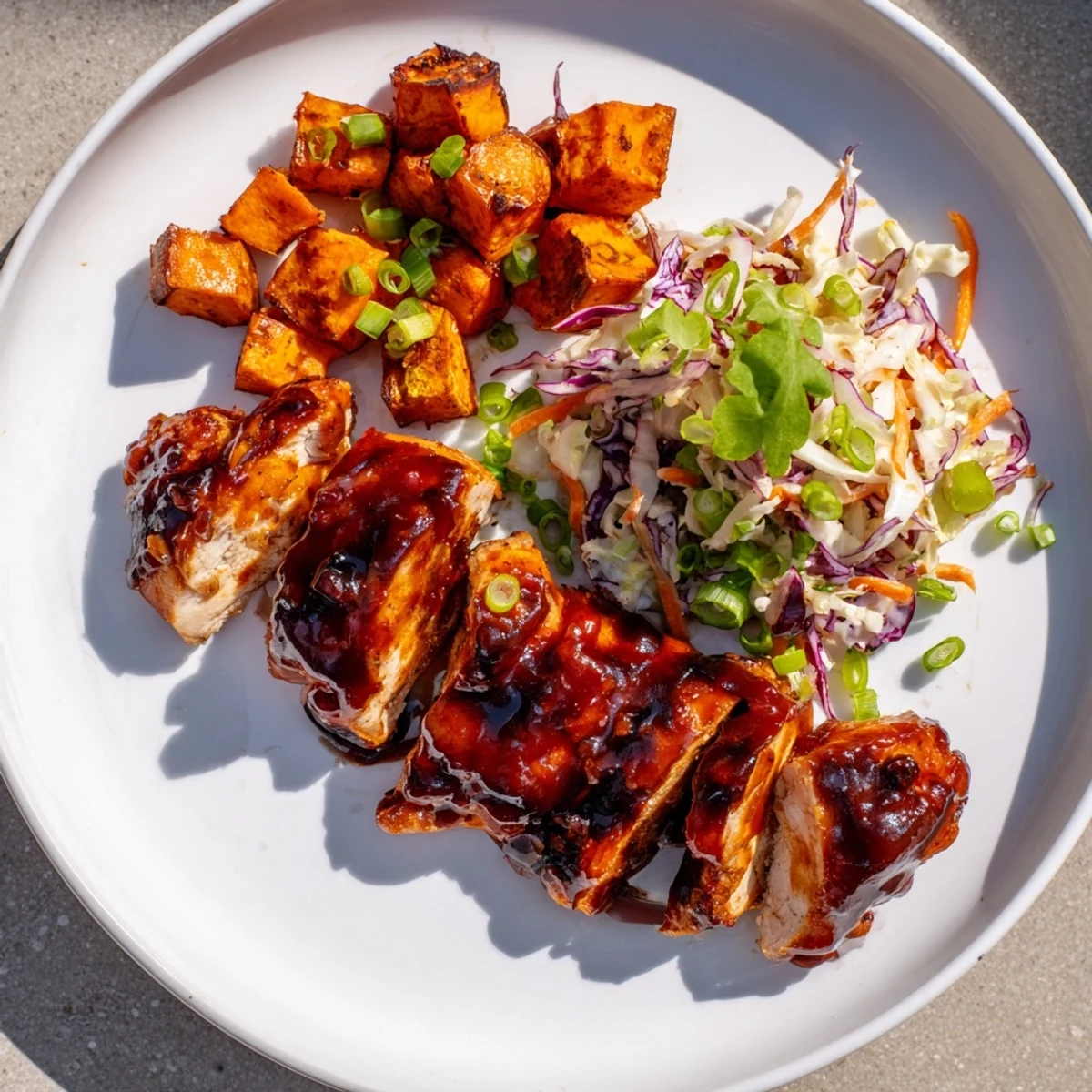 Hearty bowl featuring tender BBQ chicken sliced over caramelized sweet potatoes and fresh coleslaw