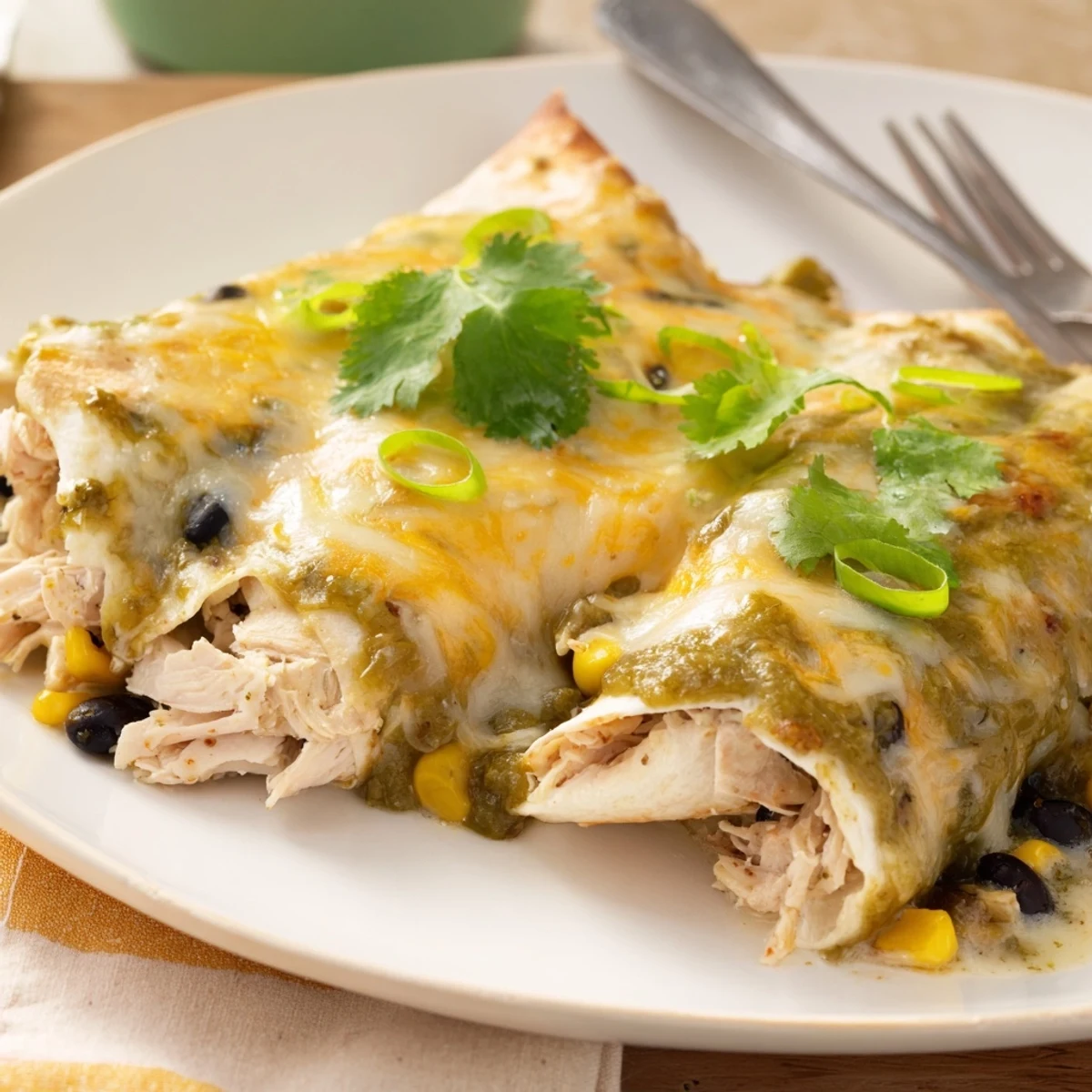 Golden baked salsa verde chicken enchiladas topped with melted Monterey Jack cheese and fresh cilantro