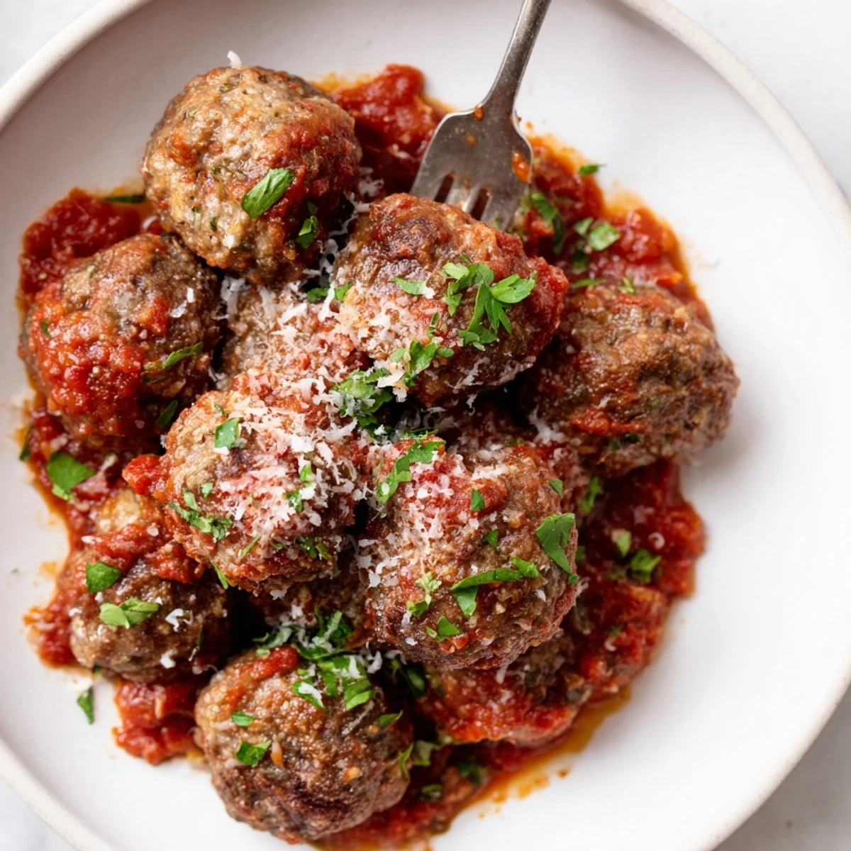 Savory Authentic Italian Meatballs swimming in herb tomato sauce alongside a plate of spaghetti
