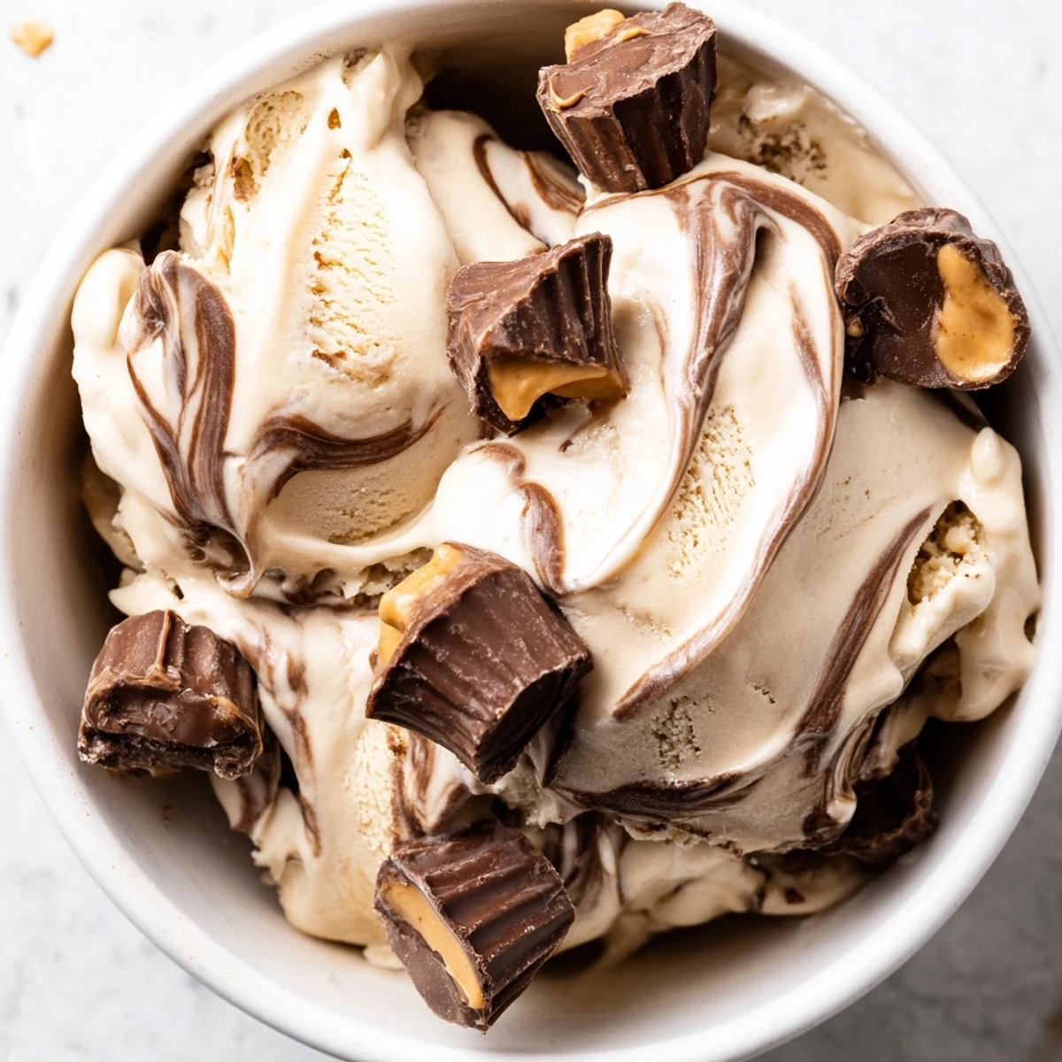 Scoop of velvety moose tracks ice cream loaded with chocolate peanut butter cups and fudge ribbons