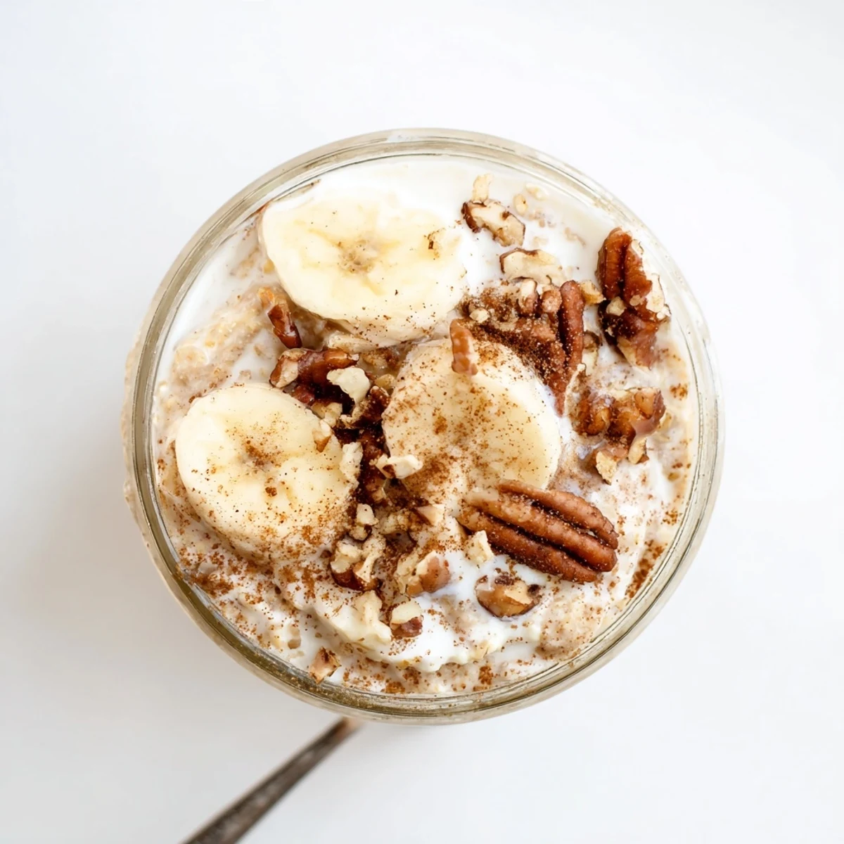 Creamy brown sugar overnight oats topped with fresh banana slices and crunchy walnuts in a glass jar