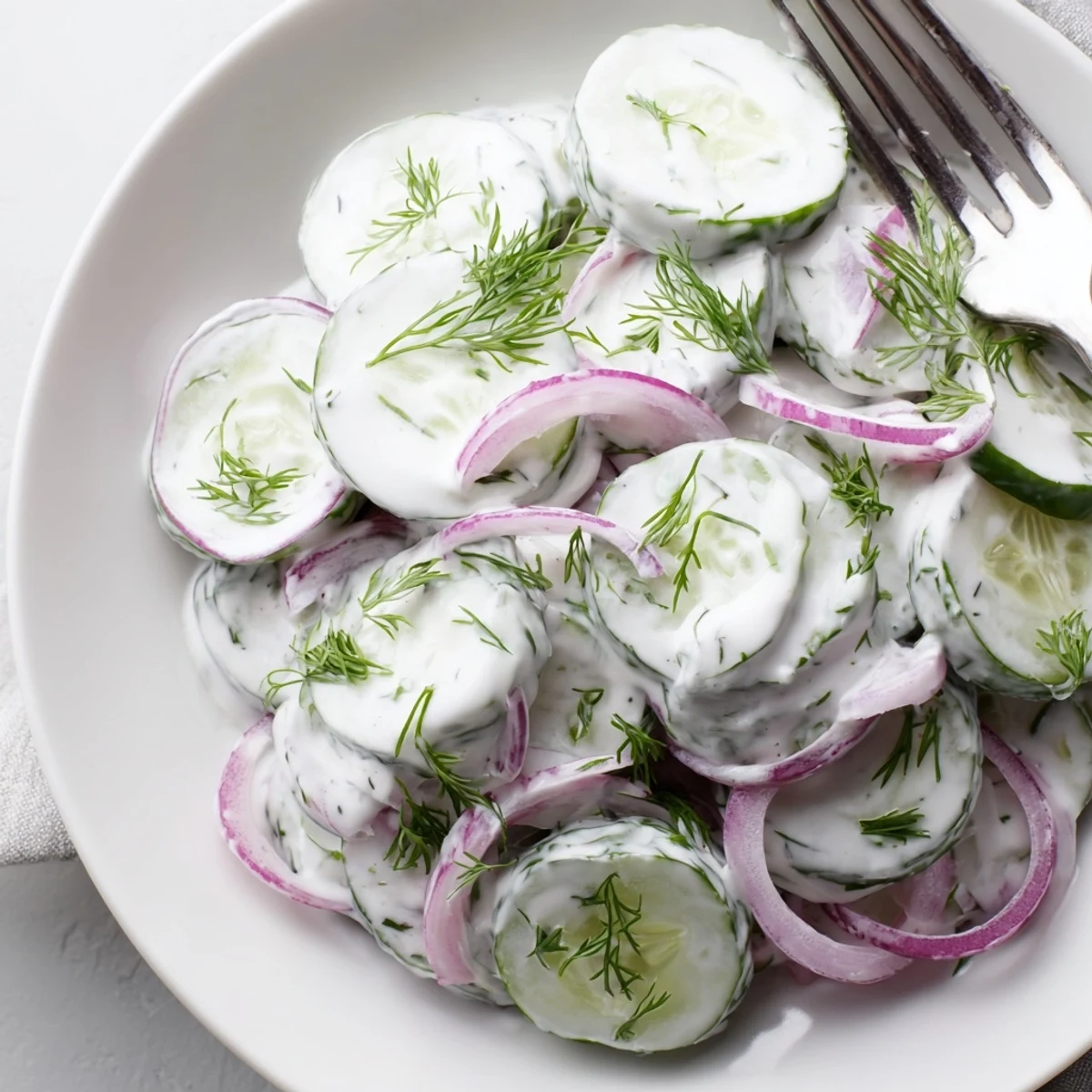 Chilled creamy cucumber salad coated in thick dressing topped with chopped fresh dill and black pepper