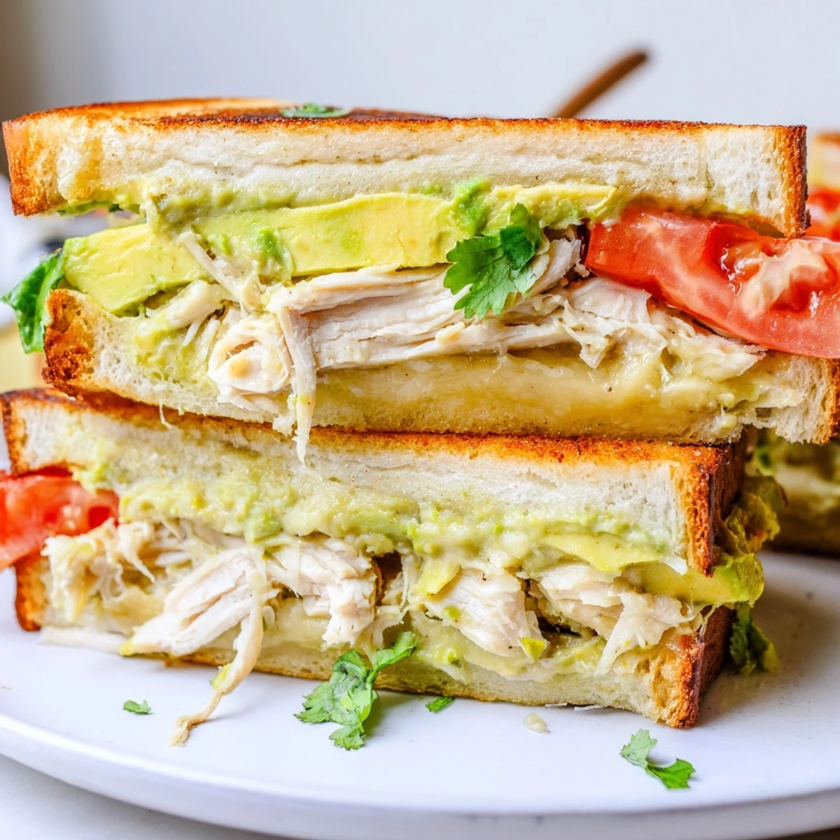Golden brown chicken avocado melt sandwich with melted cheese and fresh tomato slices on toasted sourdough bread