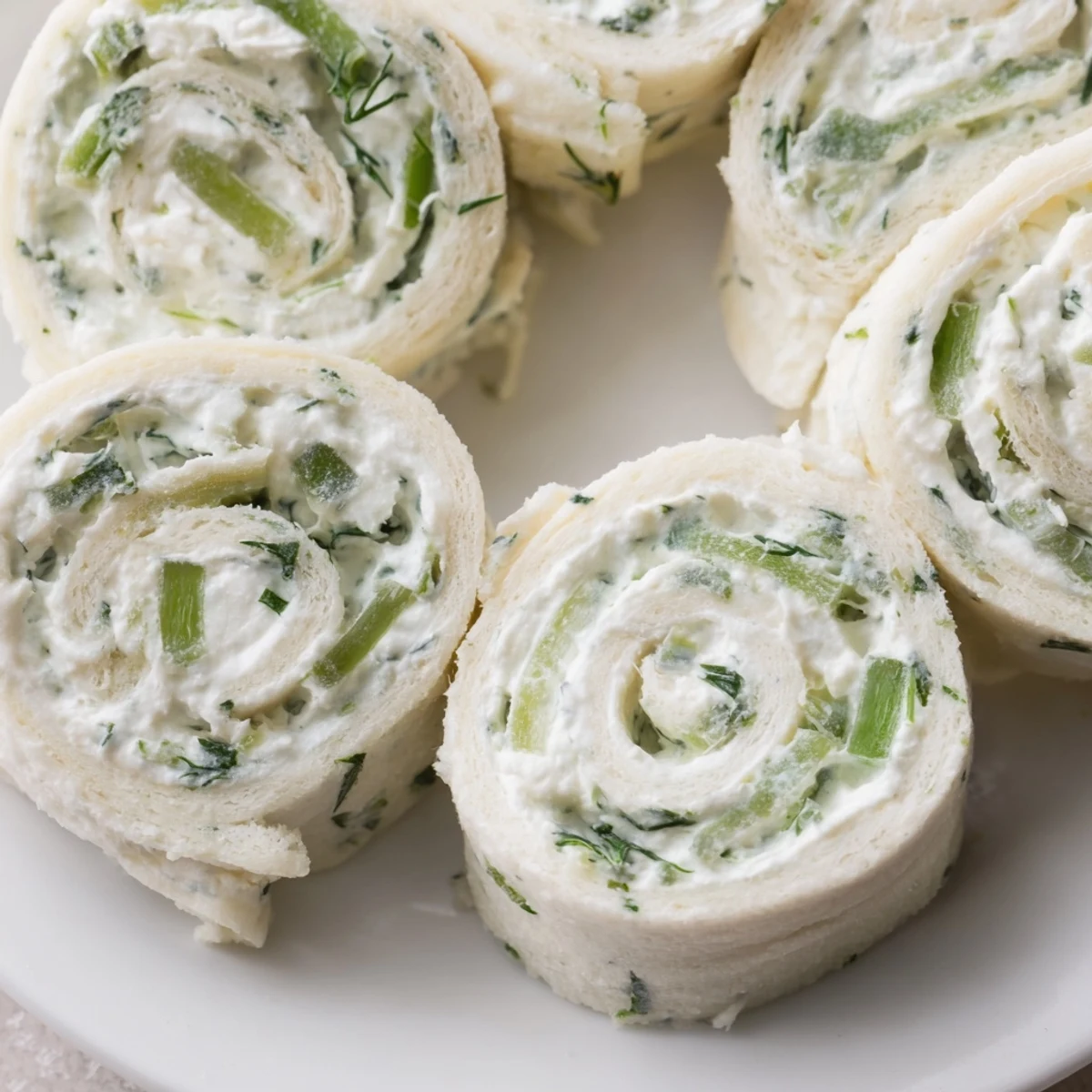 Golden spiral pinwheels stuffed with creamy dill pickle cheese filling on white platter