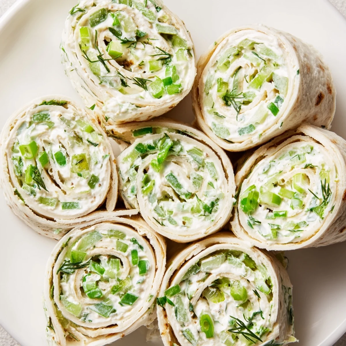 Fresh pickle dip pinwheel appetizers with green onions and herbs ready for serving