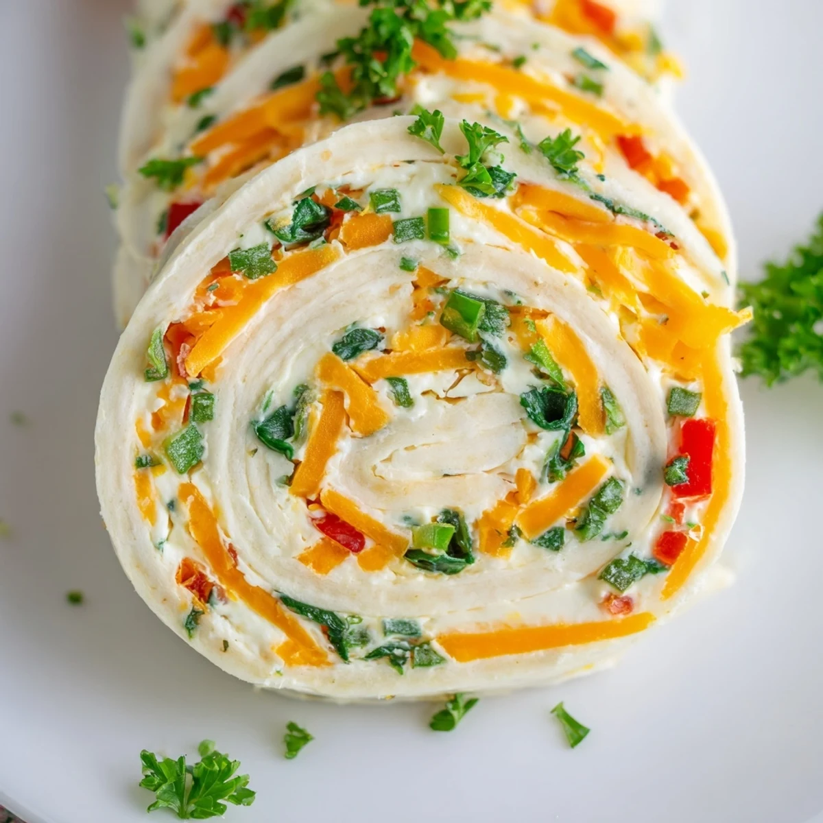 Cream cheese pinwheels with colorful diced vegetables rolled in soft flour tortillas on a white serving platter
