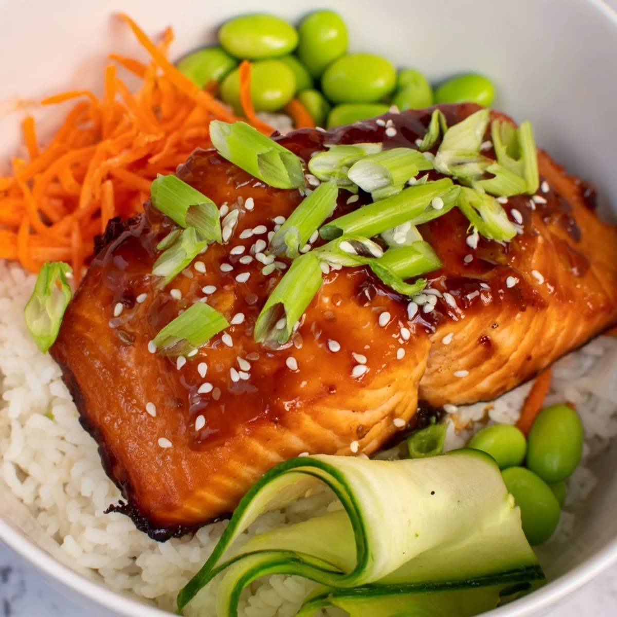 Steam rises from a honey glazed salmon bowl arranged with colorful vegetables and fluffy white rice