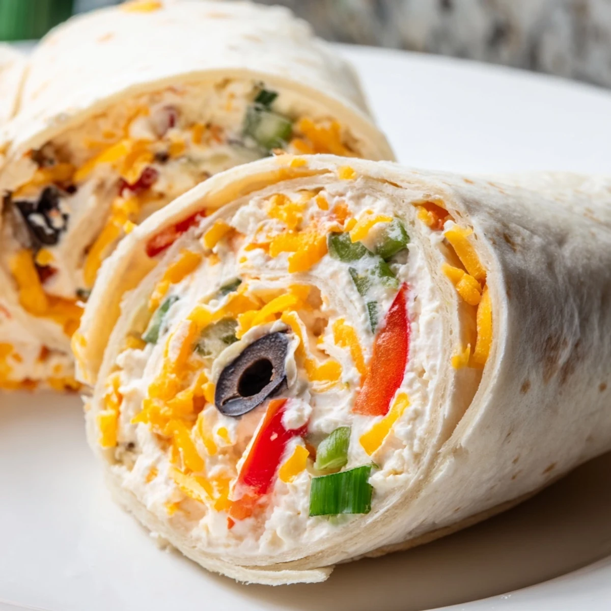 Platter of ready-to-serve easy tortilla pinwheels arranged for parties with colorful vegetable flecks visible in creamy spread