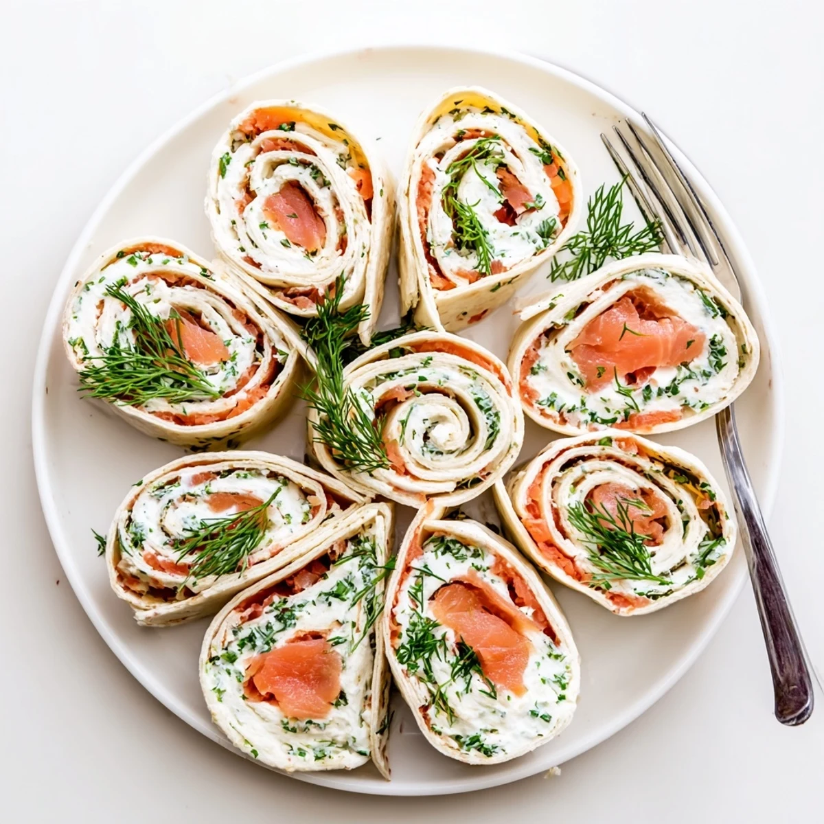 Appetizer platter of smoked salmon roll ups garnished with fresh dill and chives