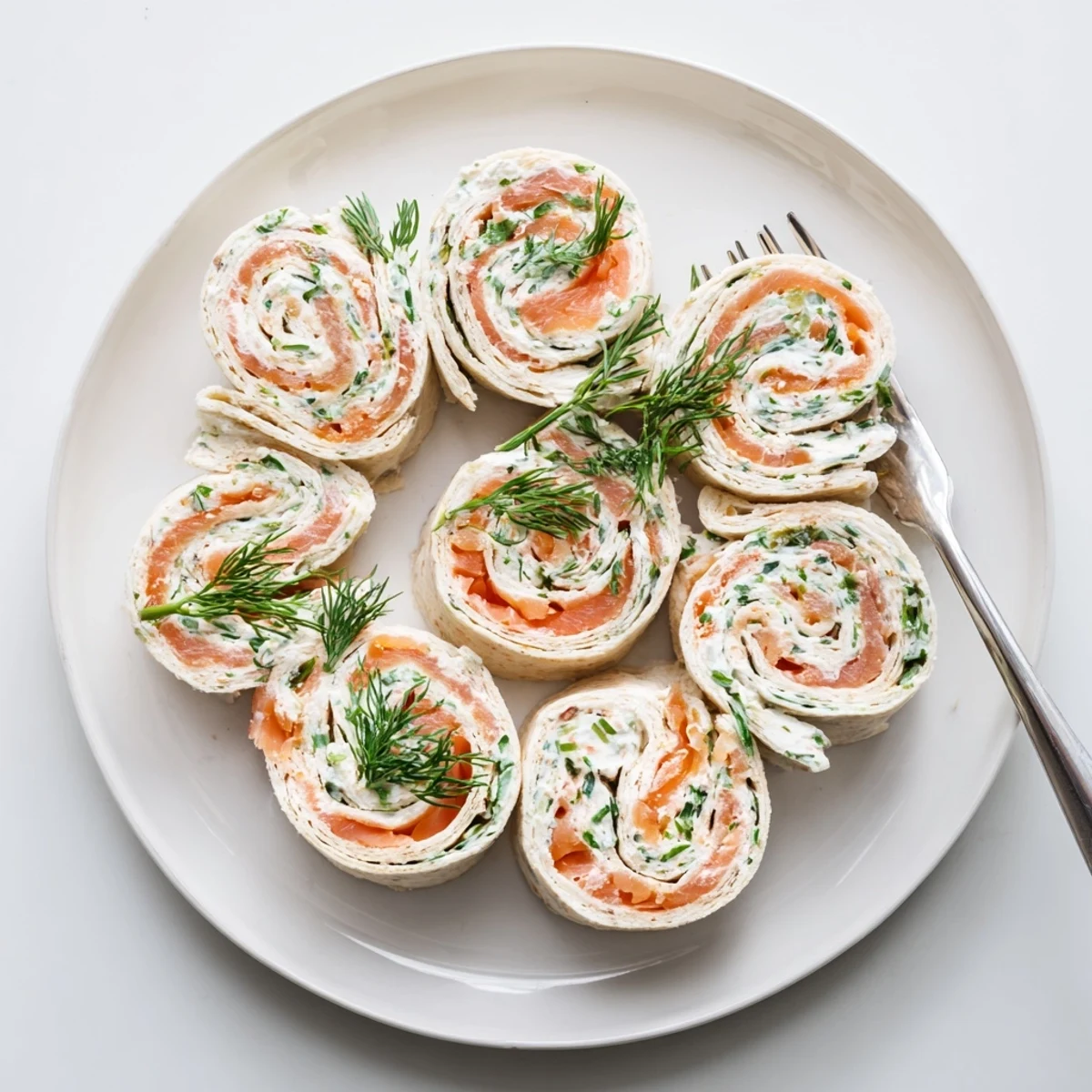 Rustic wooden board displaying spiral sliced smoked salmon roll ups with vibrant green herbs