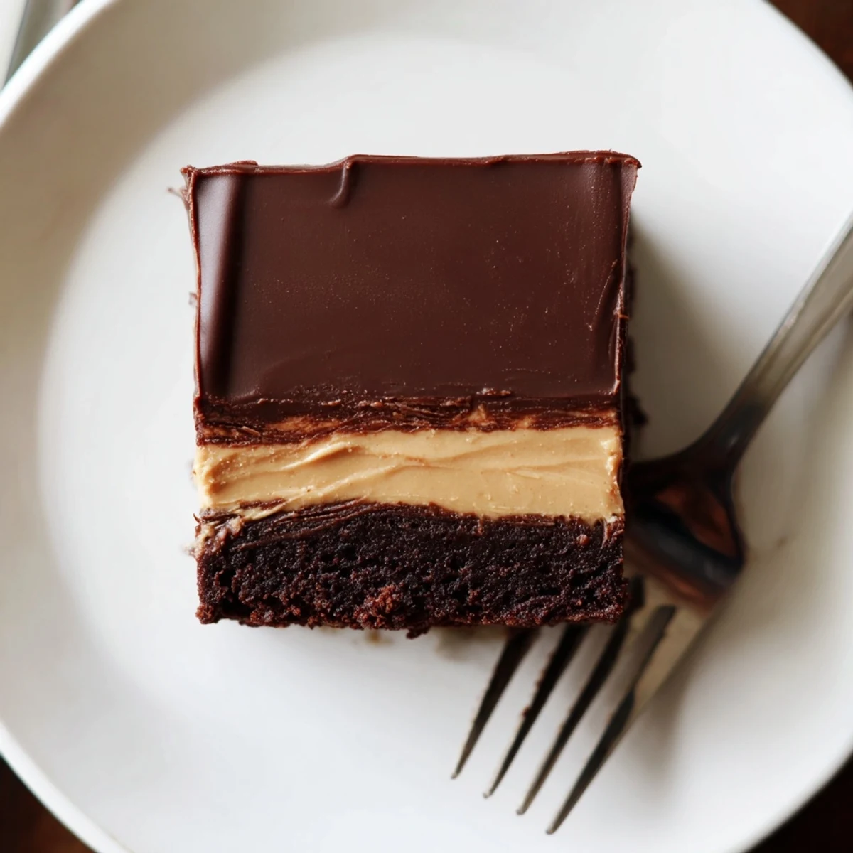 Decadent triple layered peanut butter brownies with fudgy chocolate base and glossy chocolate topping
