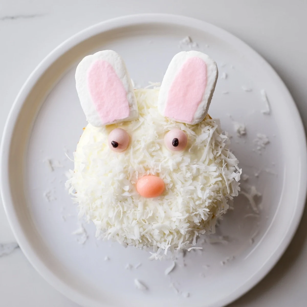 Adorable vanilla bunny cupcakes topped with fluffy coconut, pink ears, and candy eyes for Easter