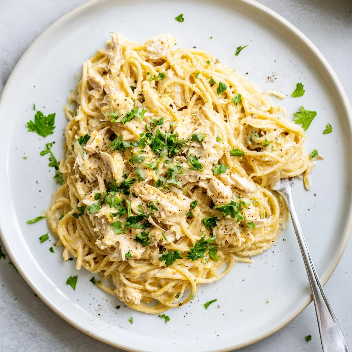 Tender slow-cooked chicken breasts swimming in rich buttery cream cheese sauce over white pasta
