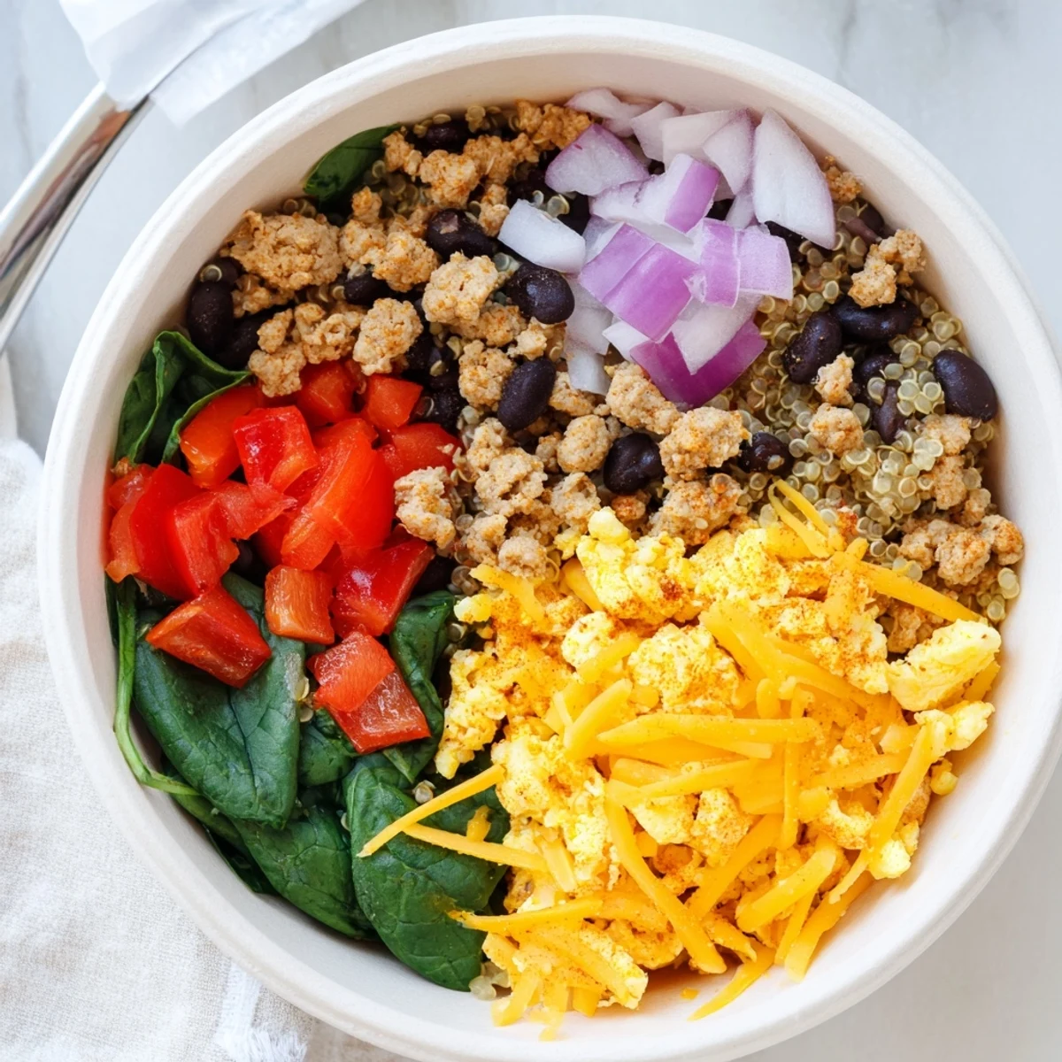 Hearty breakfast meal prep featuring high protein freezer friendly breakfast bowls topped with fluffy scrambled eggs, bell peppers, sausage, and black beans over grain base