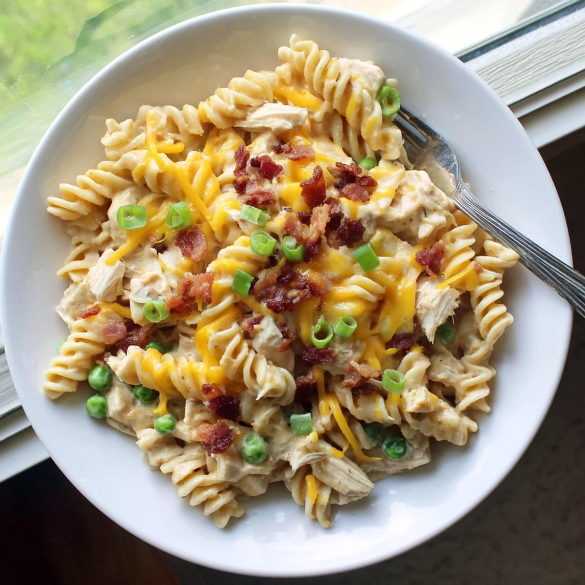 Savory crack chicken casserole bubbling in a Crock Pot with shredded cheese and crumbled bacon garnish