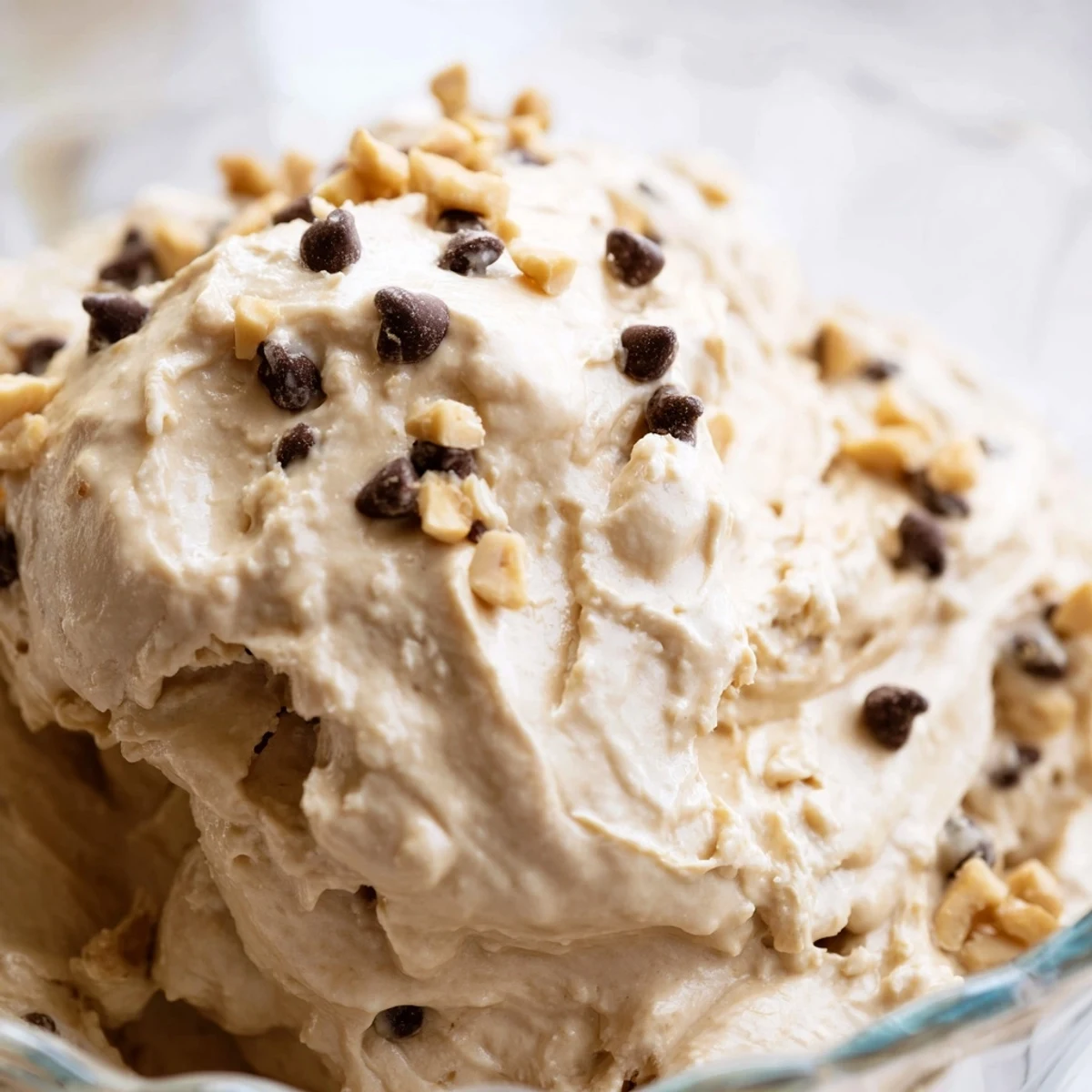 Creamy peanut butter mousse dessert with whipped texture garnished with roasted peanuts and mini chocolate chips