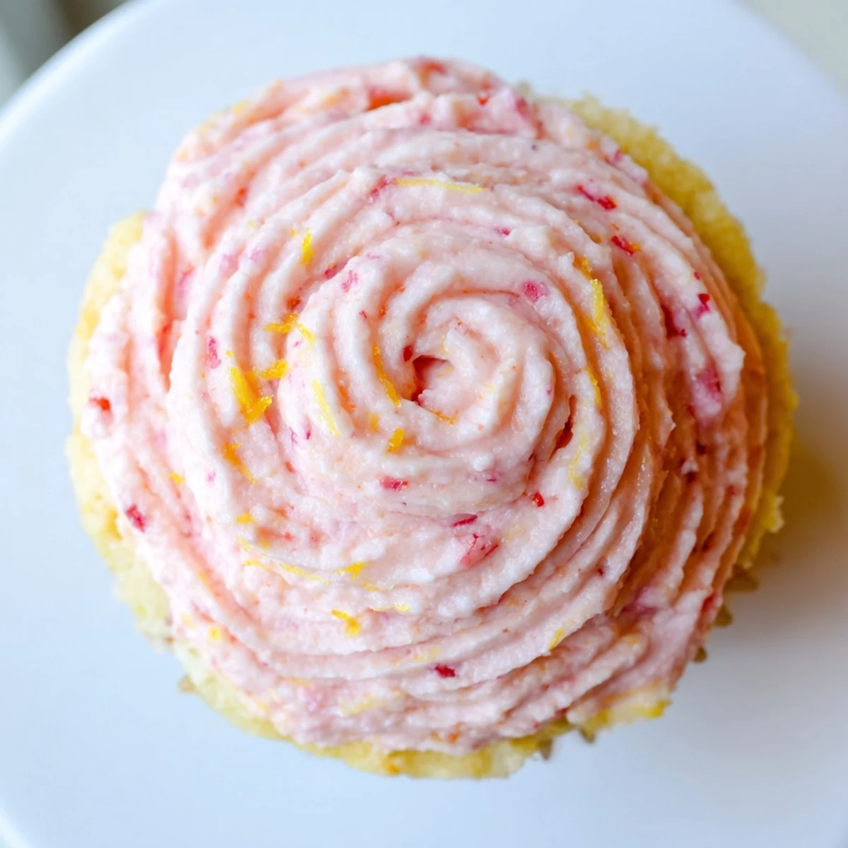 Pink strawberry lemonade cupcakes with swirled buttercream frosting topped with fresh berry slices