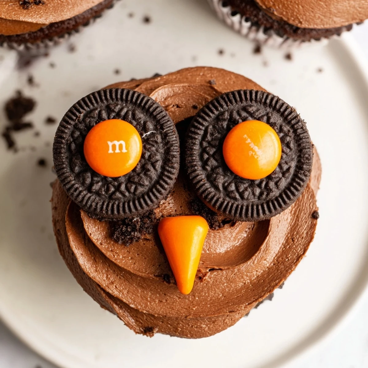 Adorable Oreo Owl Cupcakes topped with chocolate frosting and candy eyes on a rustic baking sheet