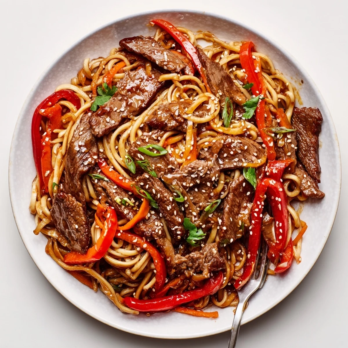 Handheld chopsticks lift Sticky Beef Noodles coated in sweet savory glaze  