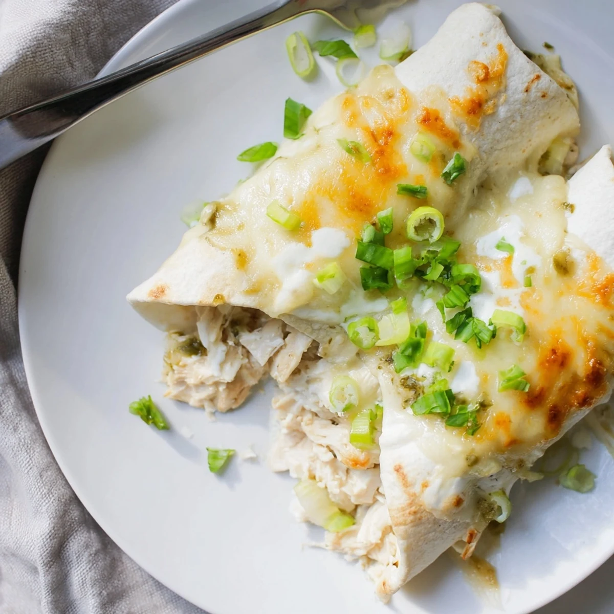 Warm Creamy White Chicken Enchiladas sliced on plate, steam rising, cilantro garnish