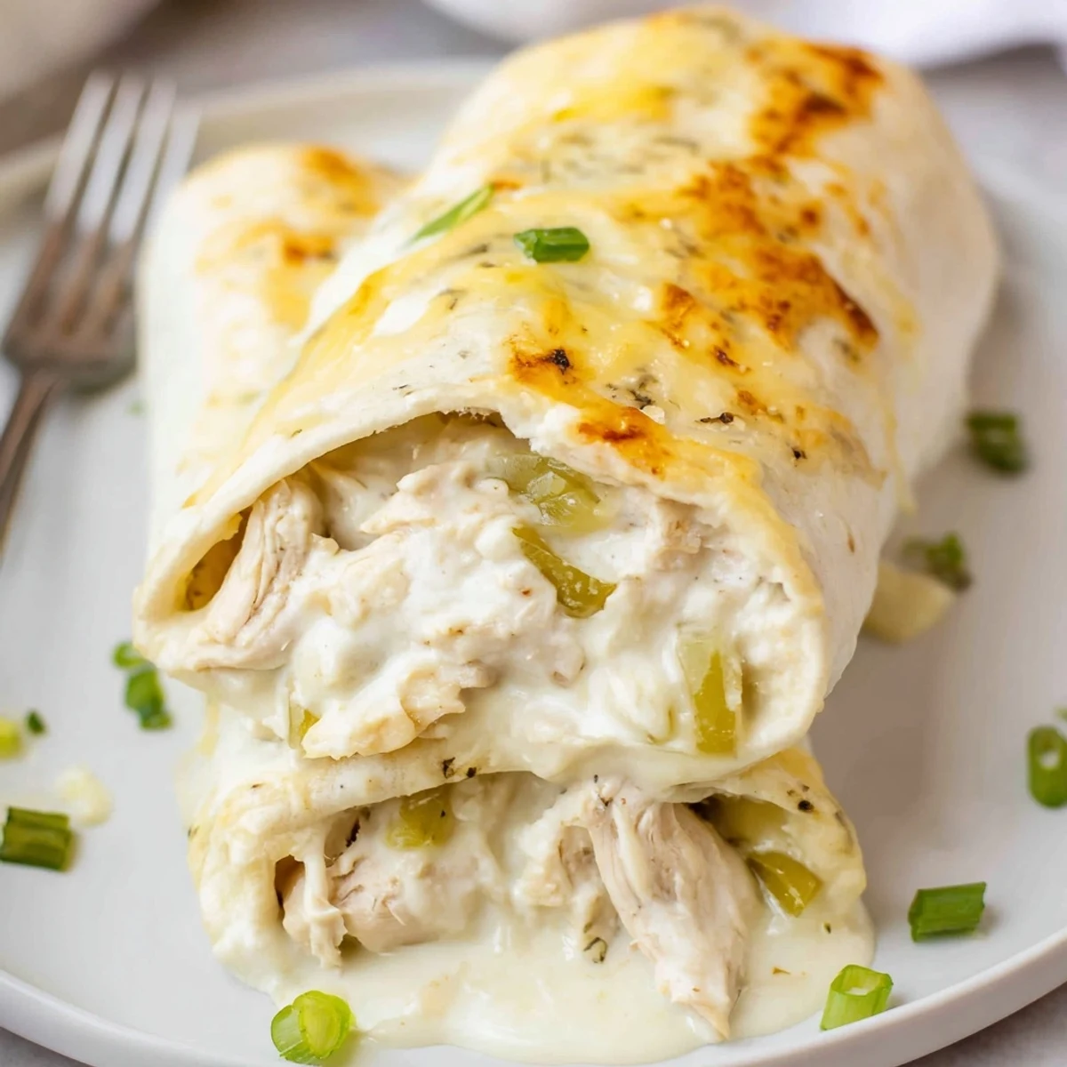 Baked Creamy White Chicken Enchiladas in casserole dish, golden edges, tempting cheese pull