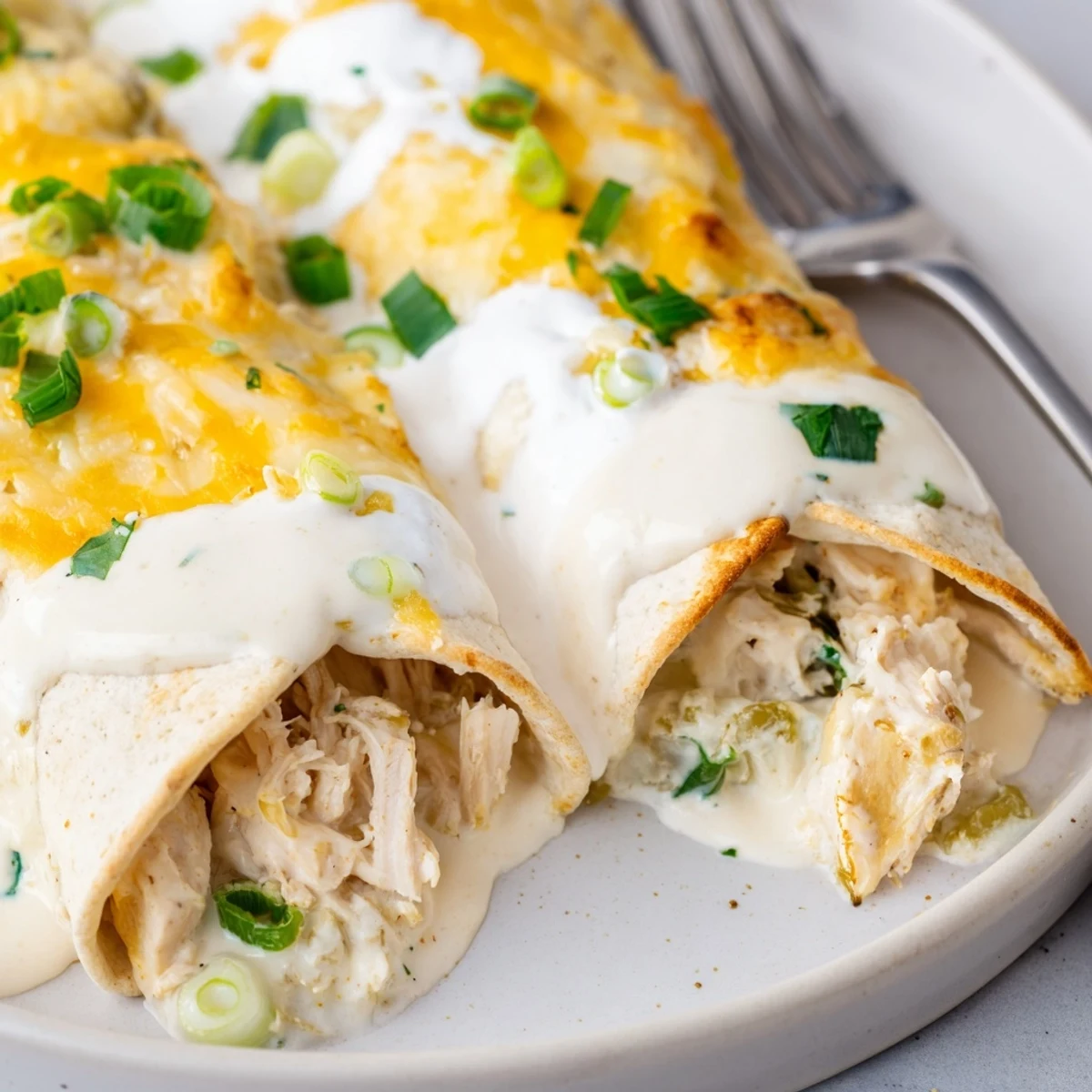 White Rotisserie Chicken Enchiladas bubbling under melted Monterey Jack and creamy white sauce