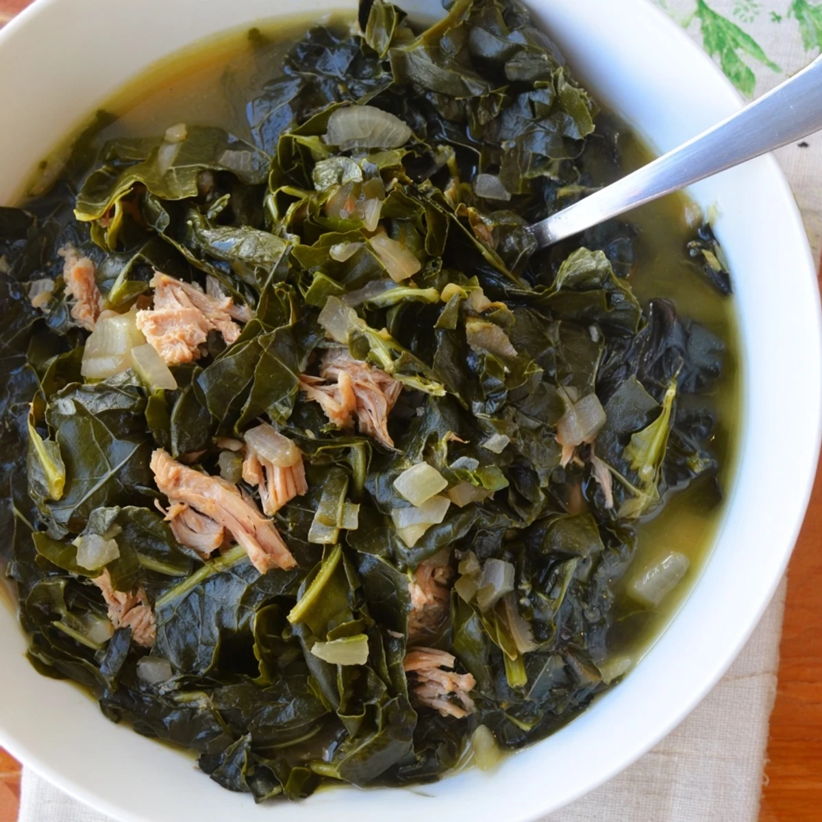 Slow-cooked Southern collard greens simmered in pot with smoky broth and tender wilted leaves