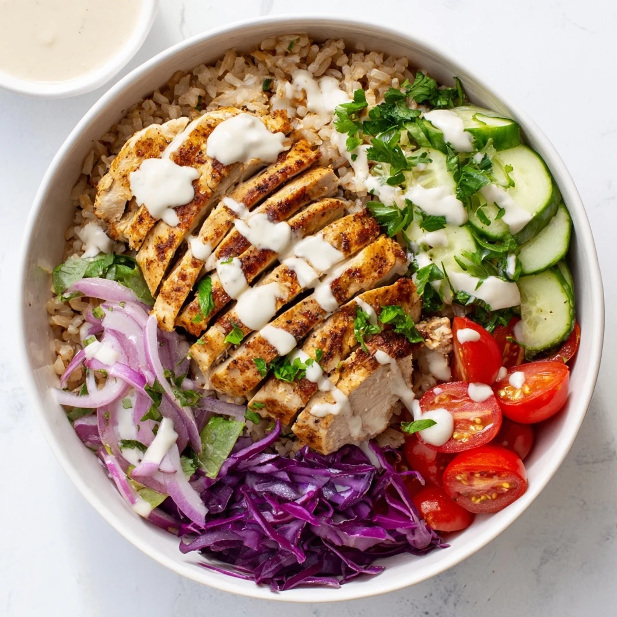 Golden spiced chicken over colorful vegetables with creamy tahini yogurt sauce drizzled on top