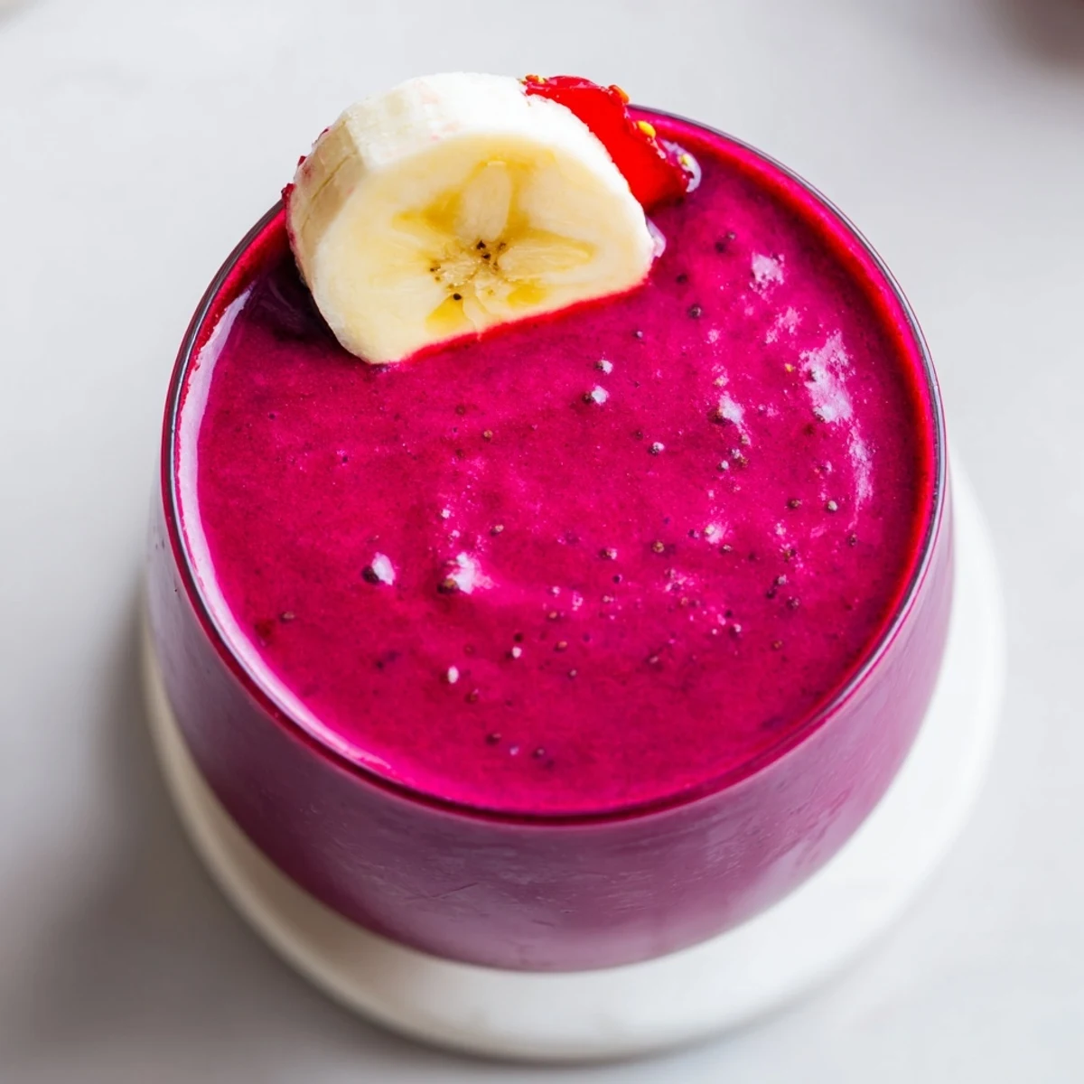 Thick purple beet smoothie topped with fresh strawberries in a clear glass