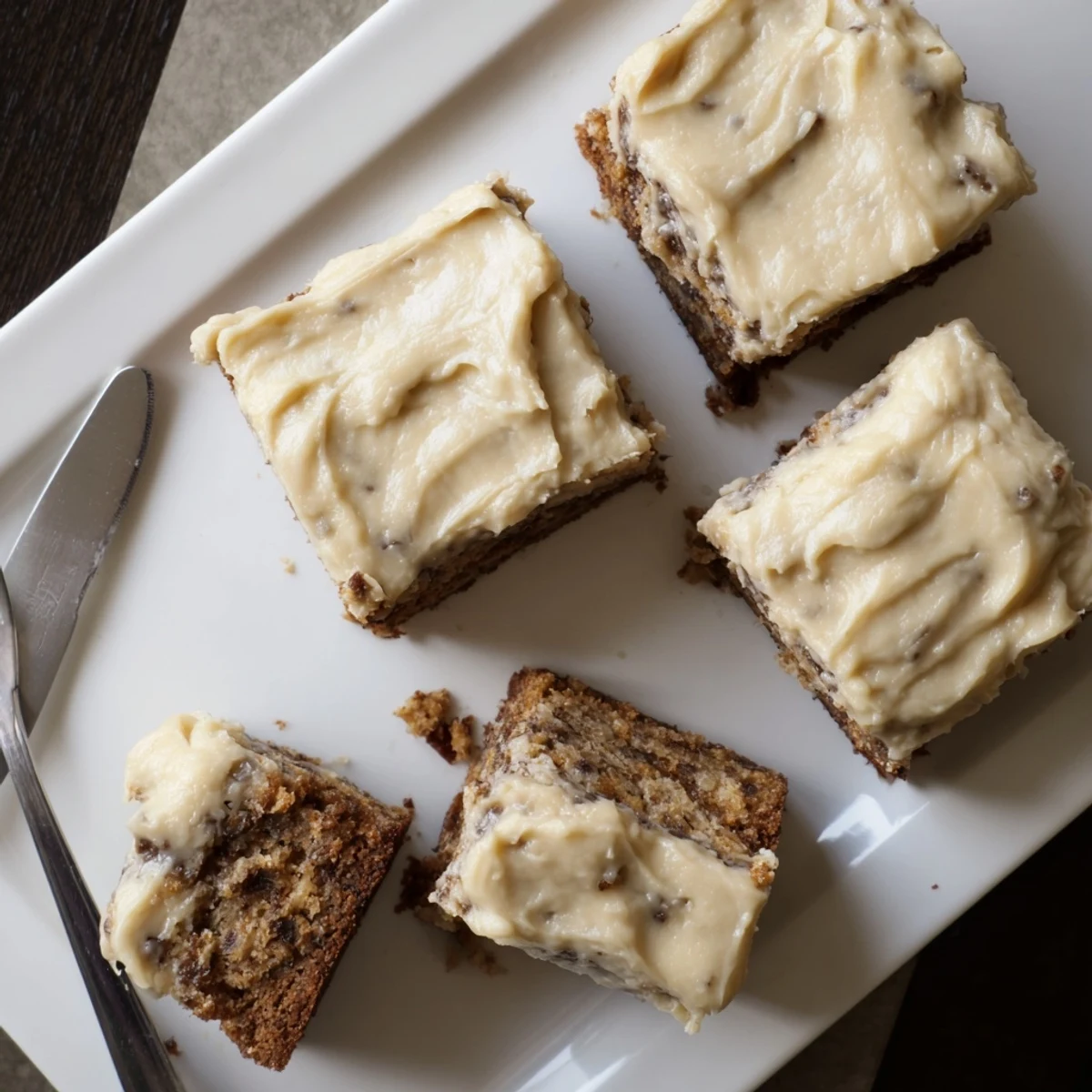 Fudgy banana bread brownies squares topped with nutty brown butter frosting on white plate