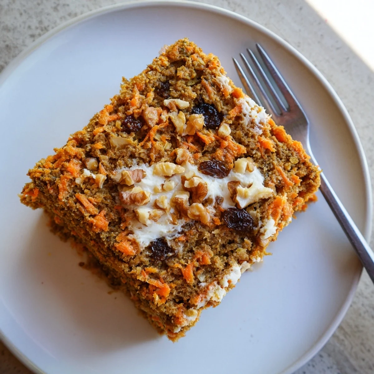 Moist flourless oatmeal carrot cake slice topped with cream cheese frosting and chopped walnuts