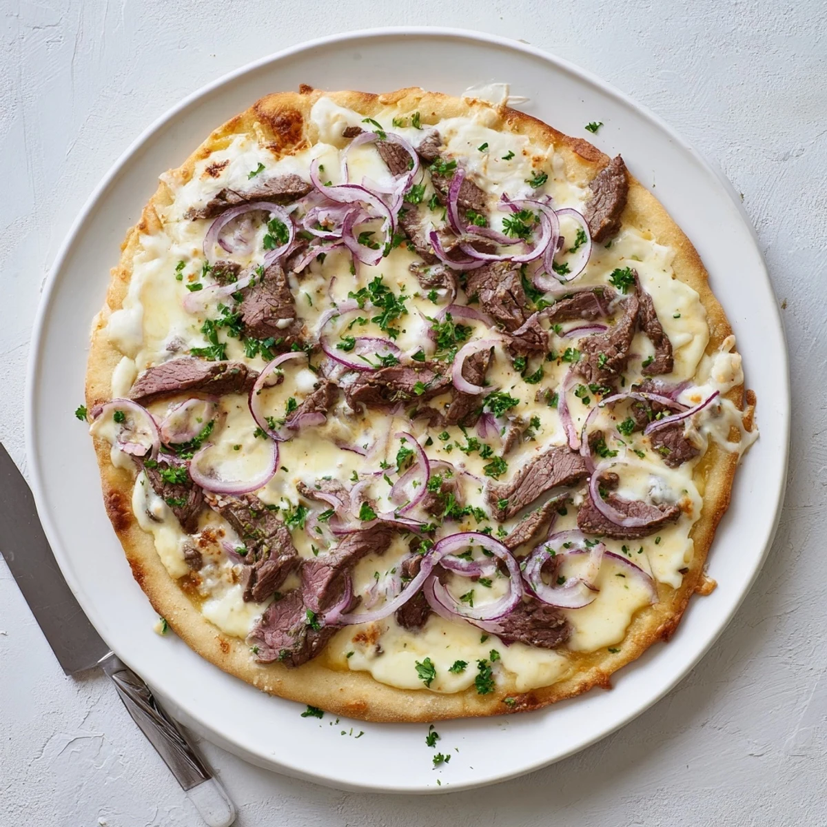 Savory Beef Alfredo Pizza with creamy white sauce, red onions, and bubbling cheese close-up