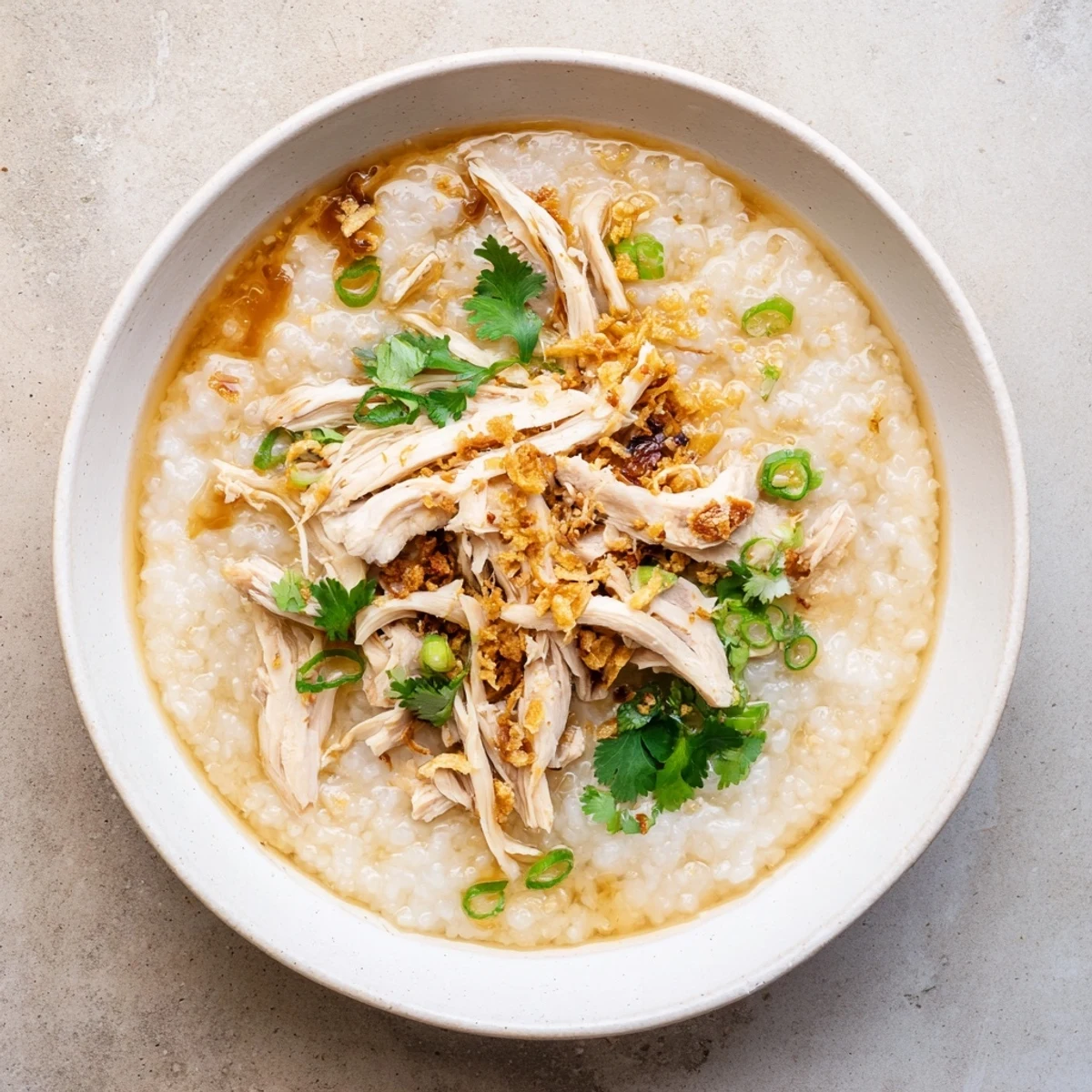 Creamy chicken congee topped with scallions in a white bowl ready for serving