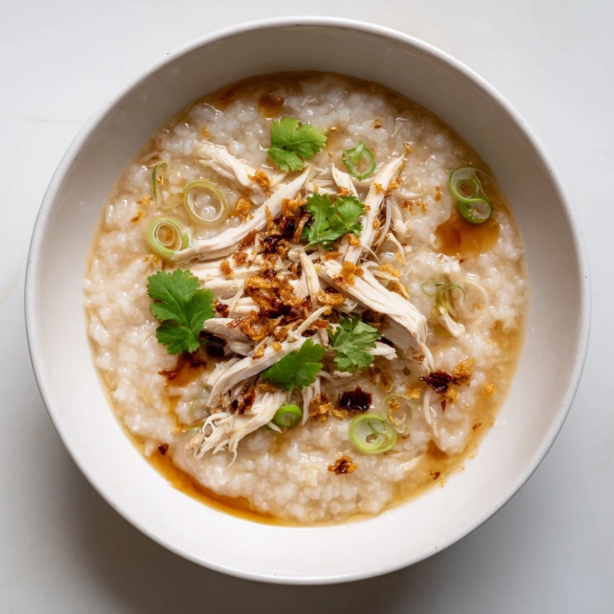Comforting Chinese chicken congee with shredded meat and fried shallots on top