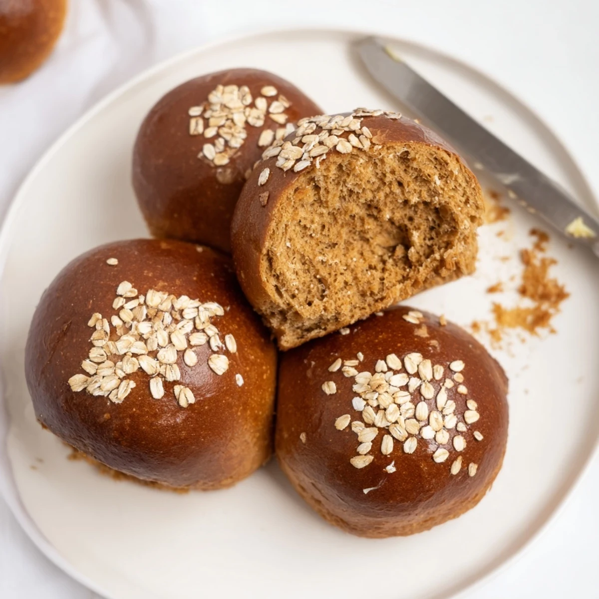 Rustic Oatmeal Molasses Dinner Rolls on parchment, oats-topped, soft interior, golden