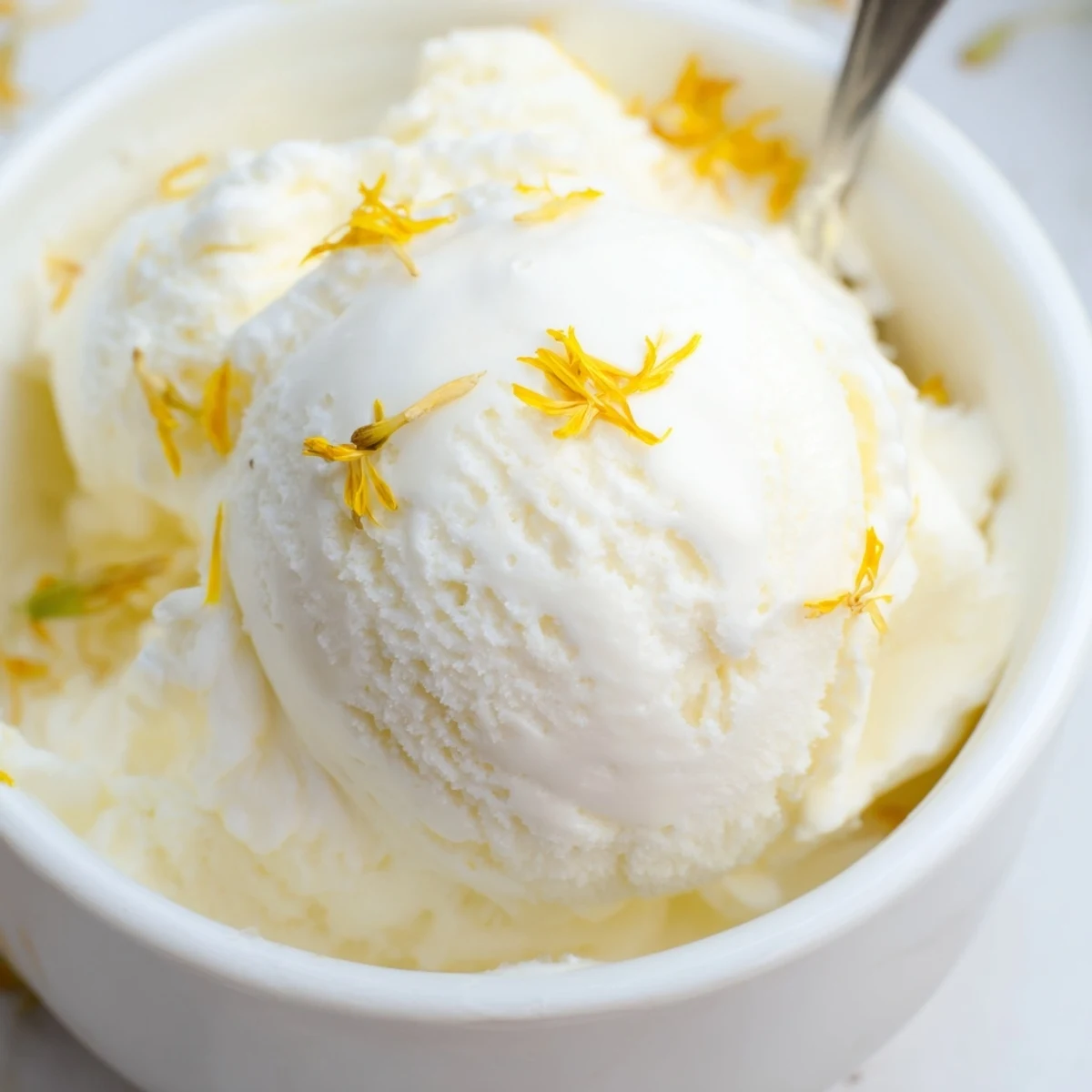 Creamy dandelion honey ice cream scooped into a bowl with golden floral honey drizzle