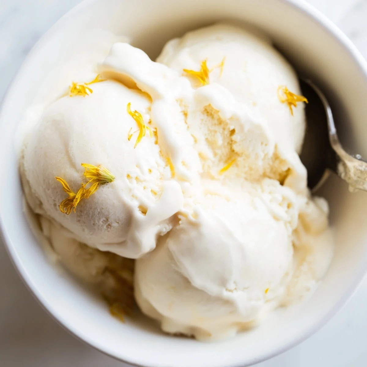 Homemade dandelion honey ice cream served in a vintage glass bowl with fresh flowers